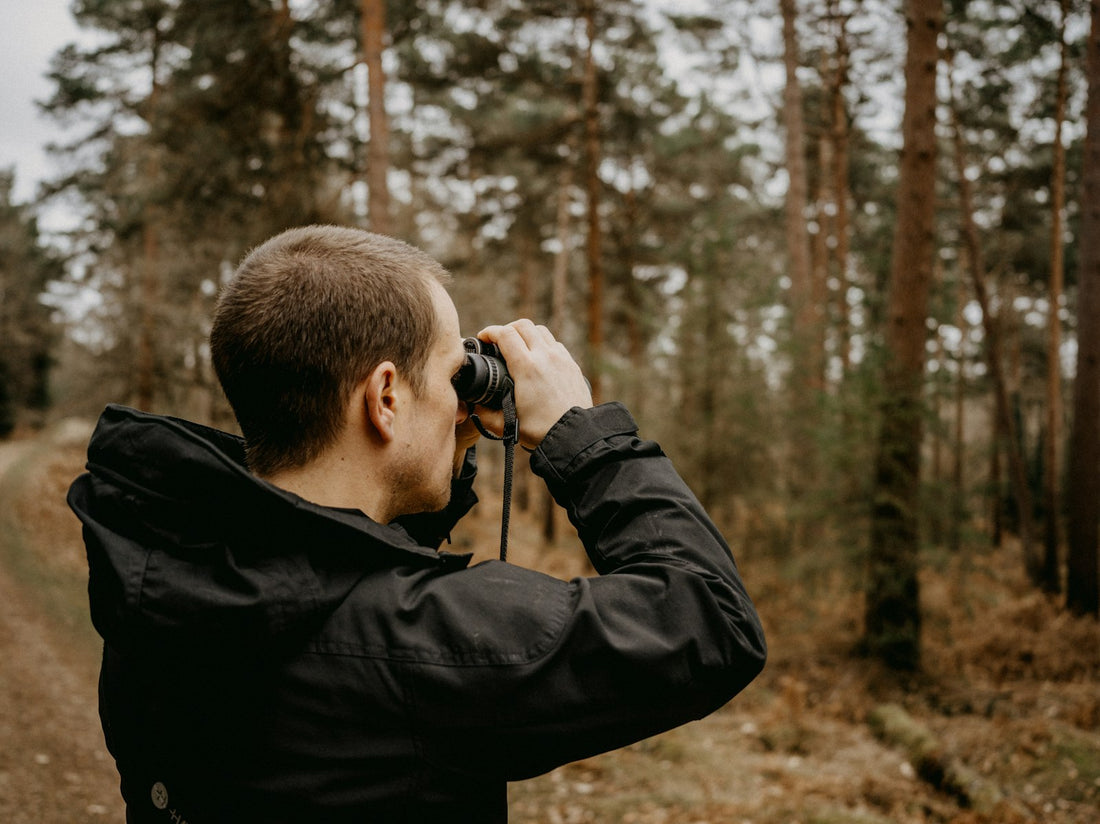 Birder looking through binoculars in the woods