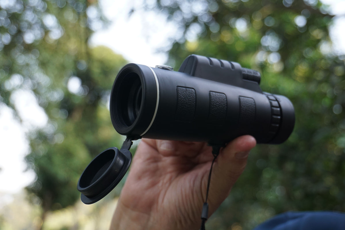 Hand holding a compact optic outdoors